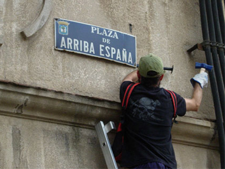 Un operario de la Ley de Memoria Histórica arranca una placa de la Plaza Arriba España