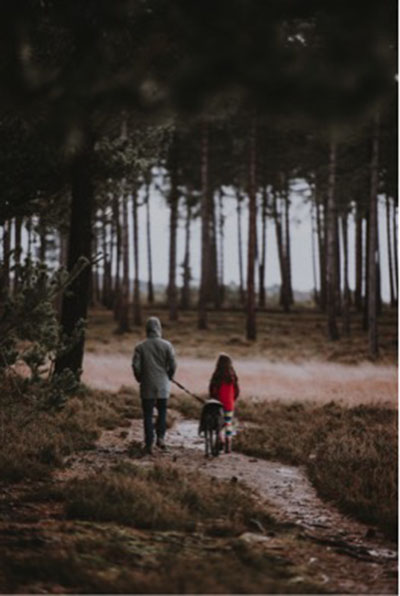 Un hombre pasea con su hija a su perro en el bosque